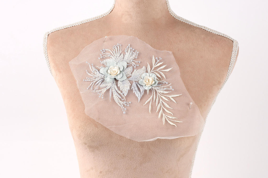 A mannequin torso with a delicate floral embroidered piece of fabric attached to it.