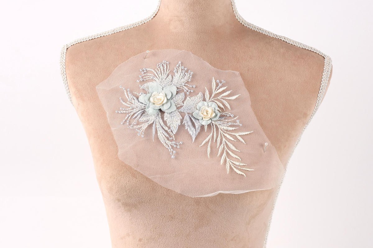 A mannequin torso with a delicate floral embroidered piece of fabric attached to it.