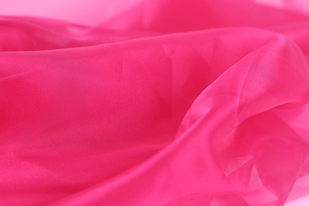 A close-up view of a soft, flowing fabric in a vibrant shade of pink.