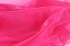 A close-up view of a soft, flowing fabric in a vibrant shade of pink.