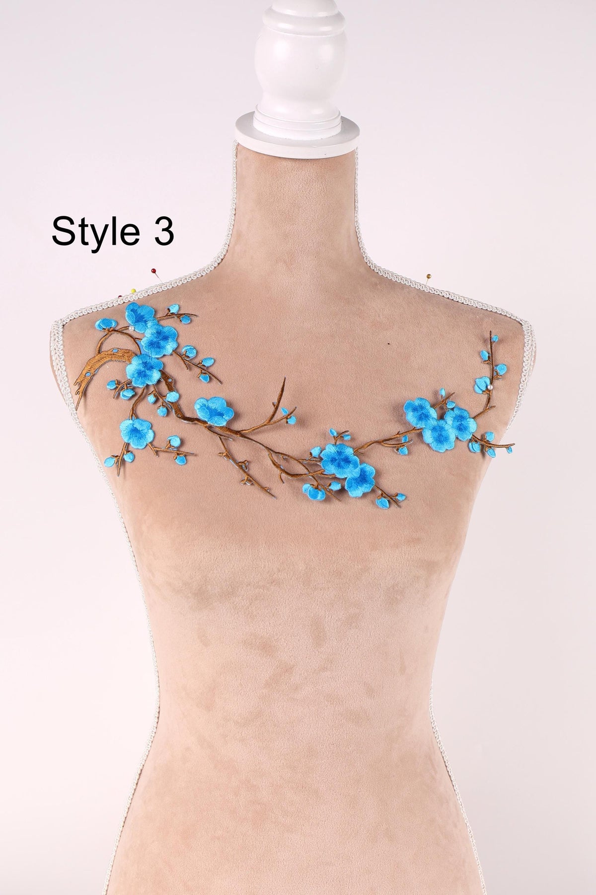 A mannequin with a floral design on its bust, featuring blue flowers and branches.