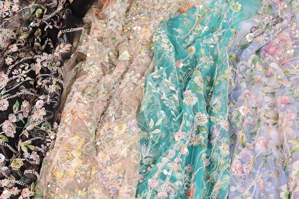 a variety of colorful, intricately embroidered fabric pieces, including black, white, and pastel-colored floral patterns.