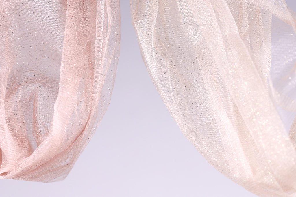 two light pink and white sheer fabric pieces hanging side by side against a light purple background.