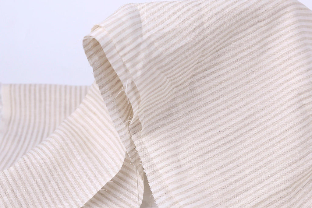 A close-up view of a fabric with horizontal stripes in various shades of beige and white.
