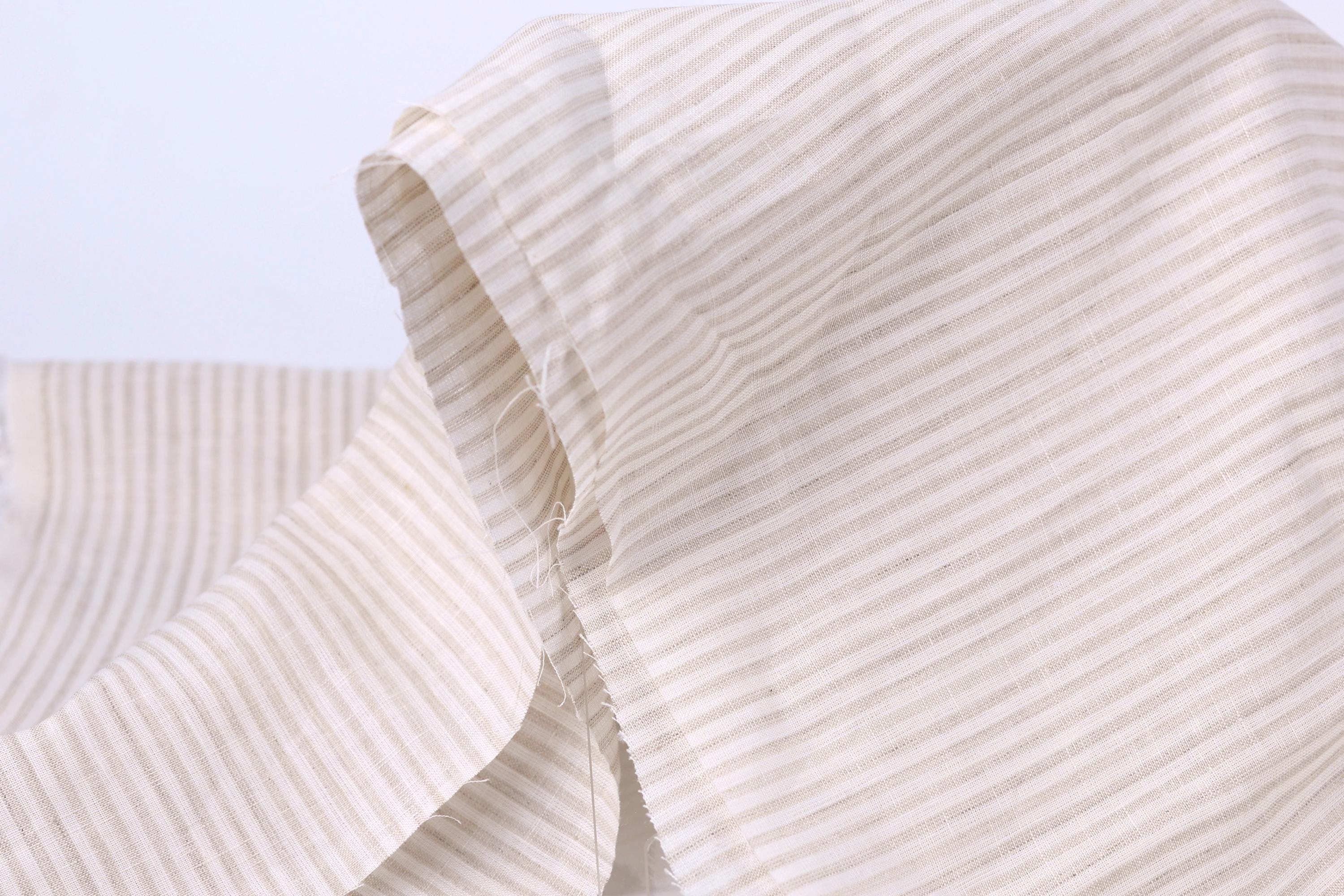 A close-up view of a fabric with horizontal stripes in various shades of beige and white.