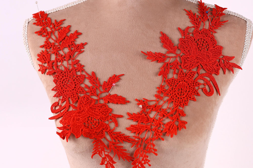 a mannequin with a red, intricately designed lace overlay on its bust.