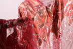 A close-up view of a red, sequined dress with a flowing, draped design.