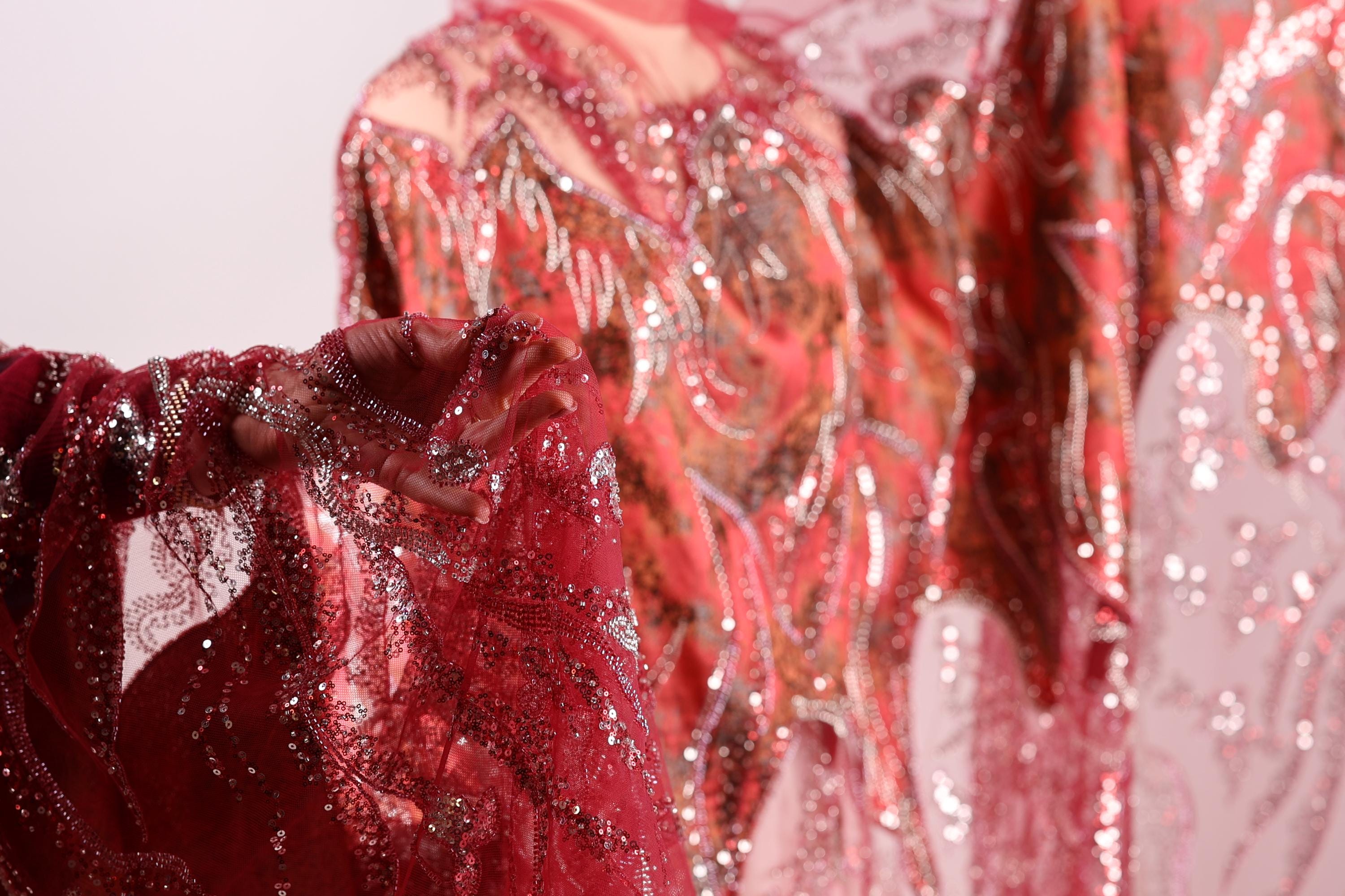 A close-up view of a red, sequined dress with a flowing, draped design.