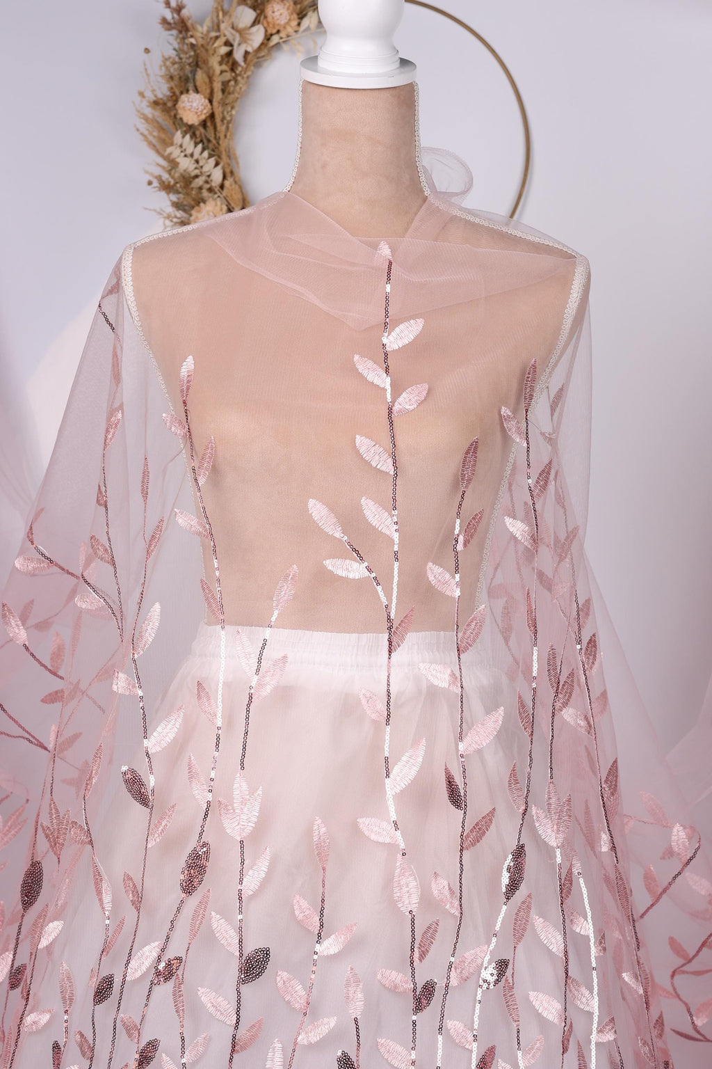 A mannequin wearing a pink and white floral dress with a sheer overlay.