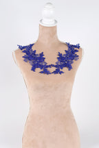 A mannequin wearing a beige dress with a blue floral necklace.