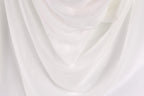 The image is a close-up of a white fabric, possibly a sheer or sheer-like material, with a soft, flowing texture.