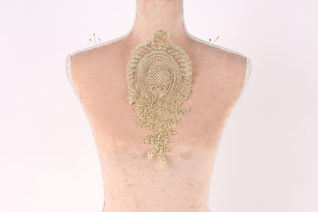 a mannequin with a decorative gold embroidered piece on its back.