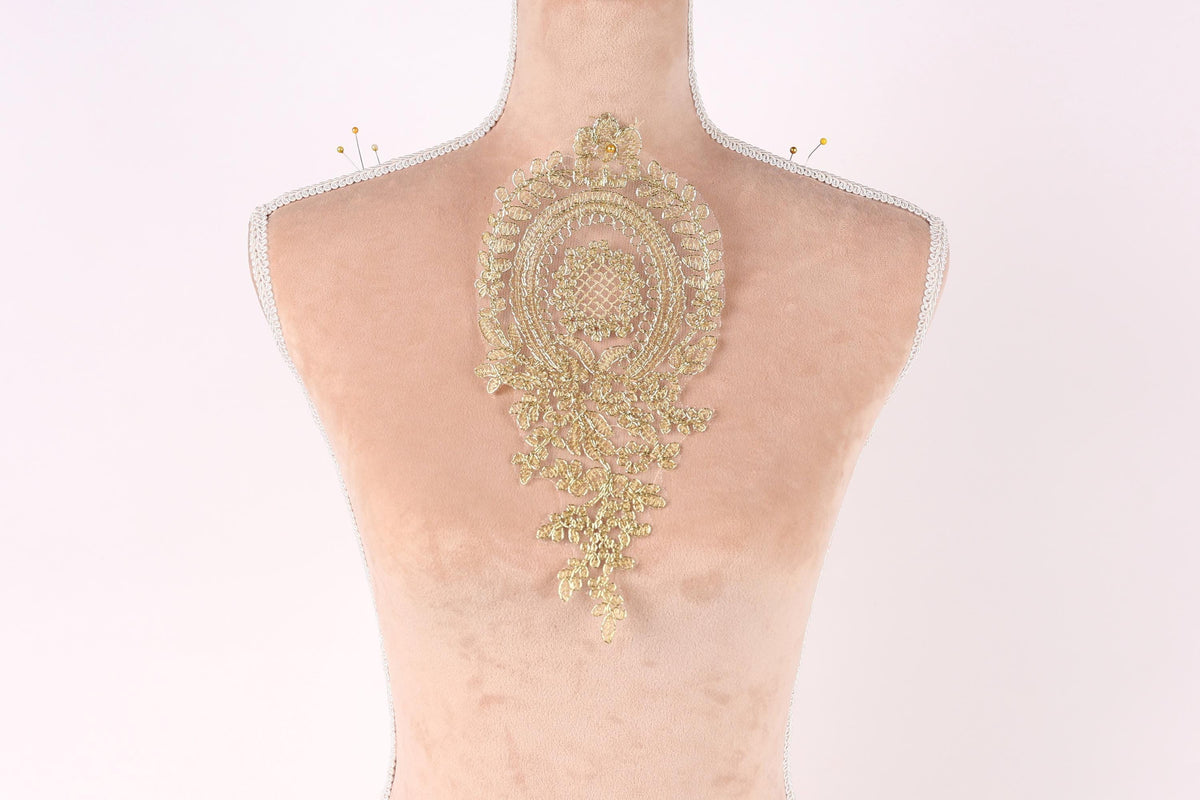 a mannequin with a decorative gold embroidered piece on its back.