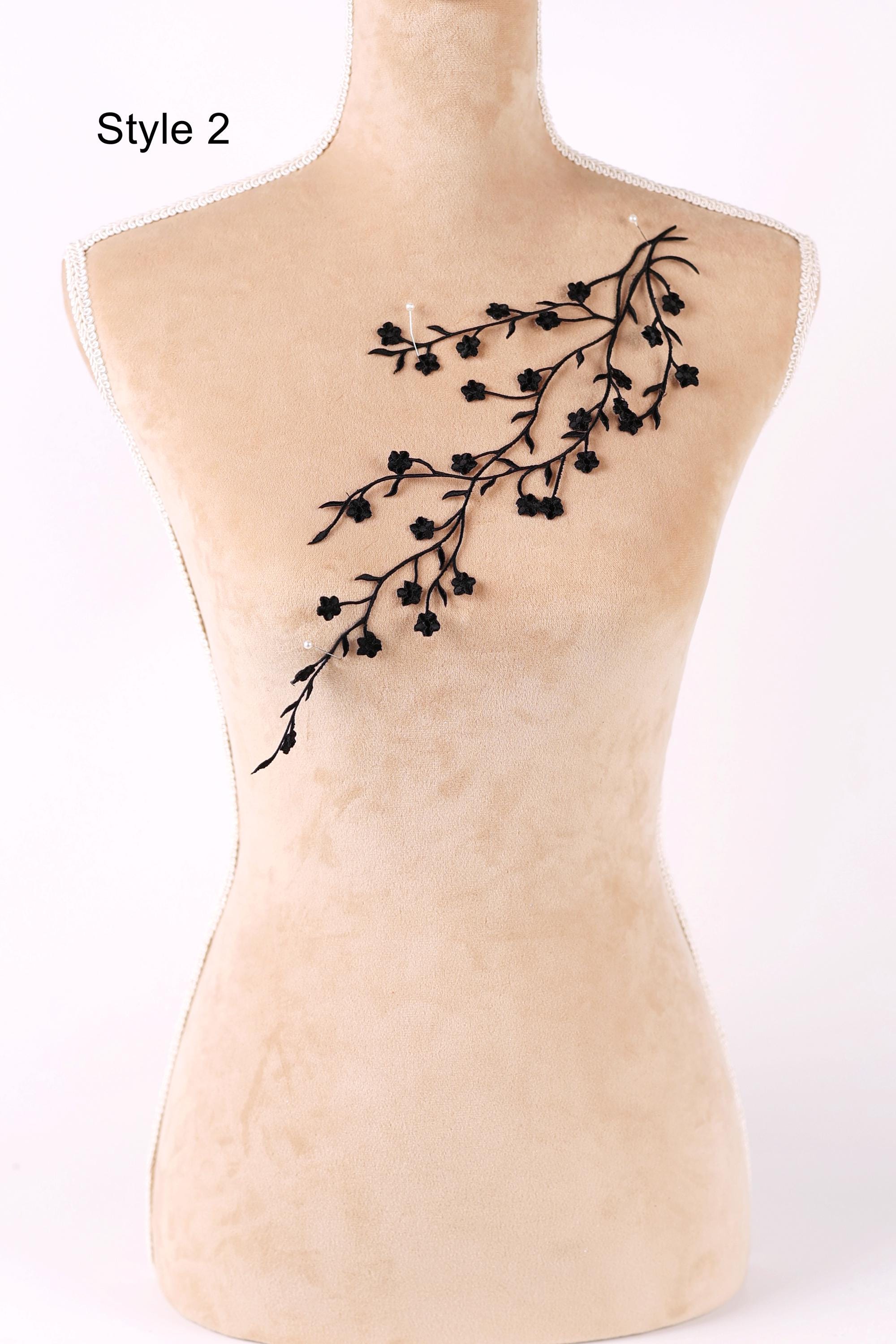 A mannequin with a beige body and a black branch-like design on its chest.