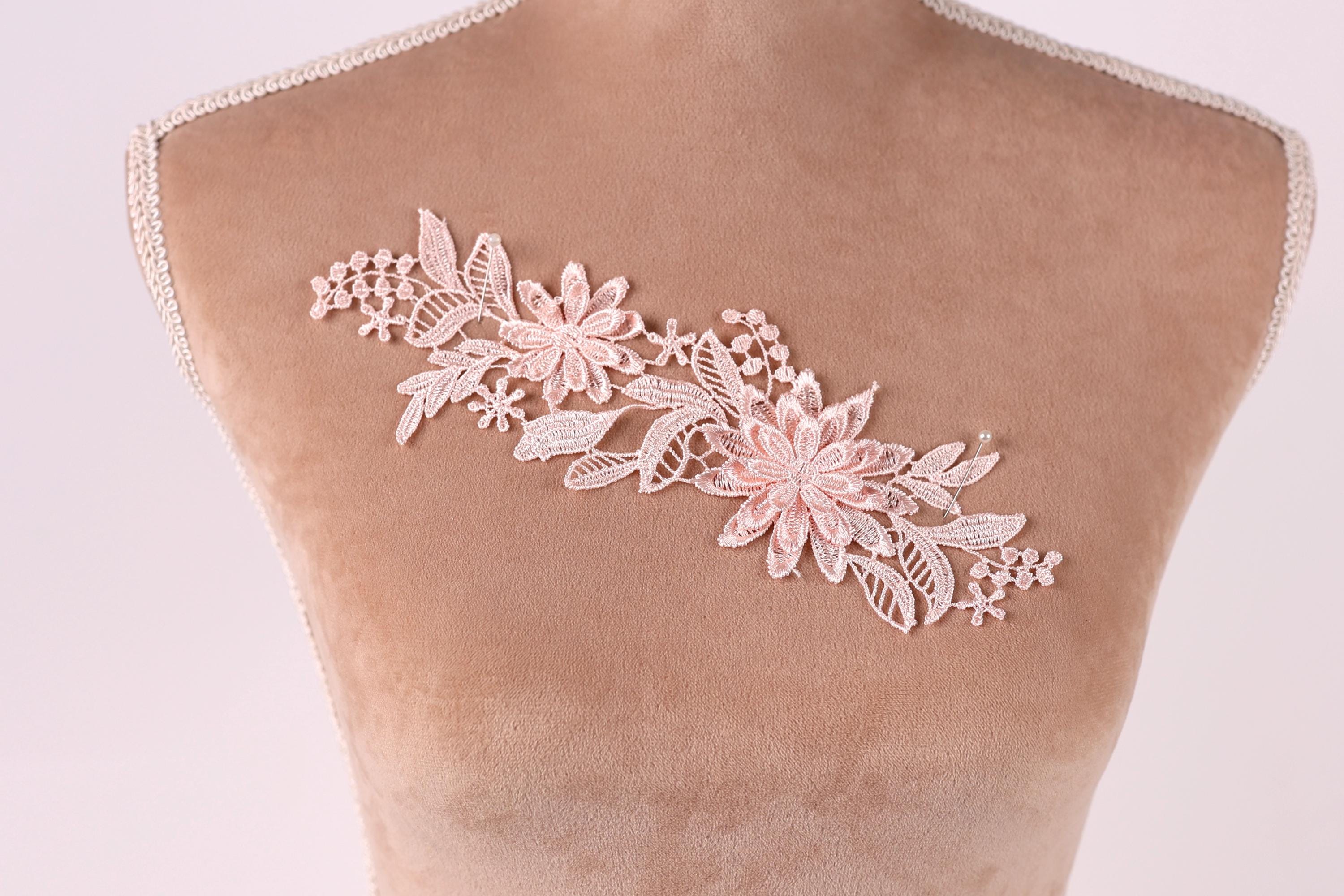 A mannequin torso with a delicate, floral lace piece sewn onto it.