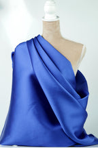 A mannequin is wearing a blue satin fabric draped over its body.