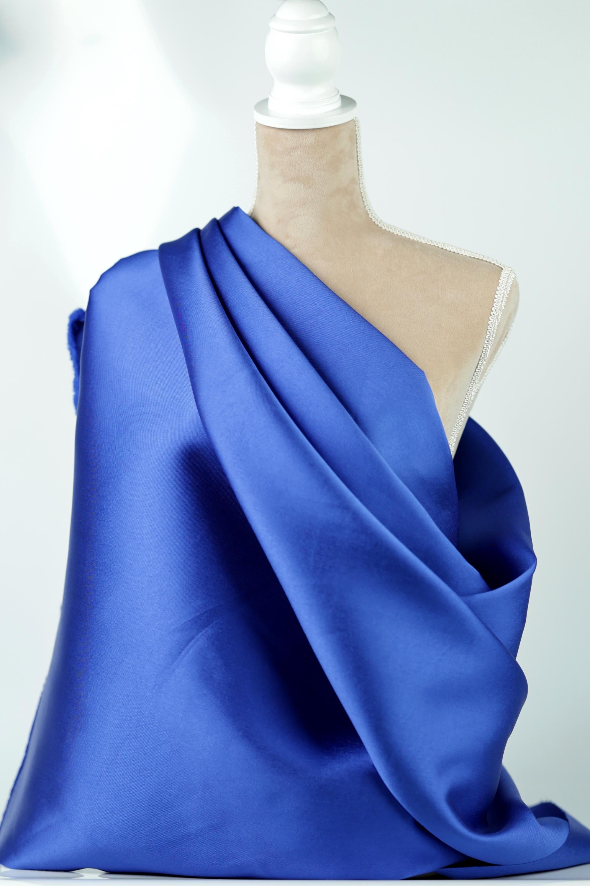 A mannequin is wearing a blue satin fabric draped over its body.