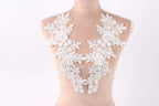 A mannequin wearing a white lace dress with intricate floral patterns.