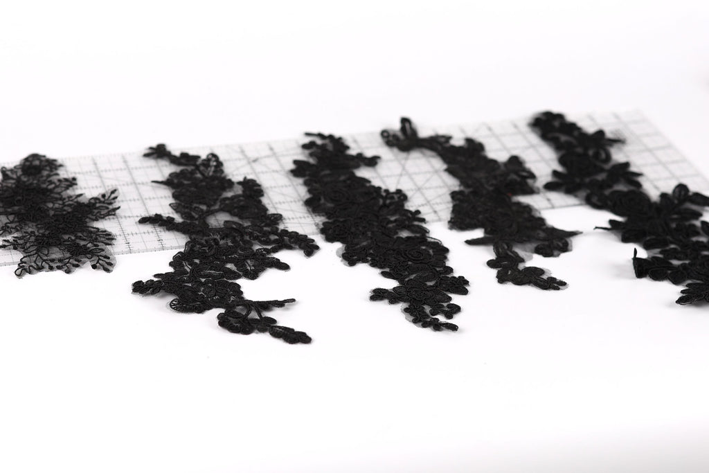 a collection of black lace pieces arranged on a white background.