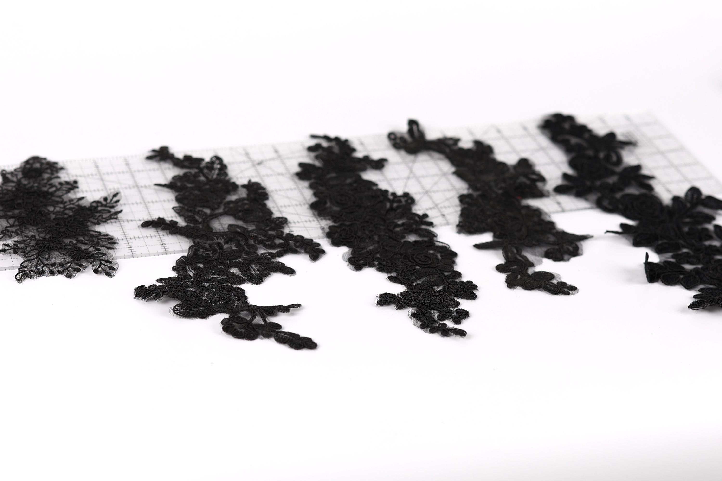 a collection of black lace pieces arranged on a white background.