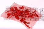 a collection of red flowers and leaves, including roses and ferns, arranged on a transparent surface.