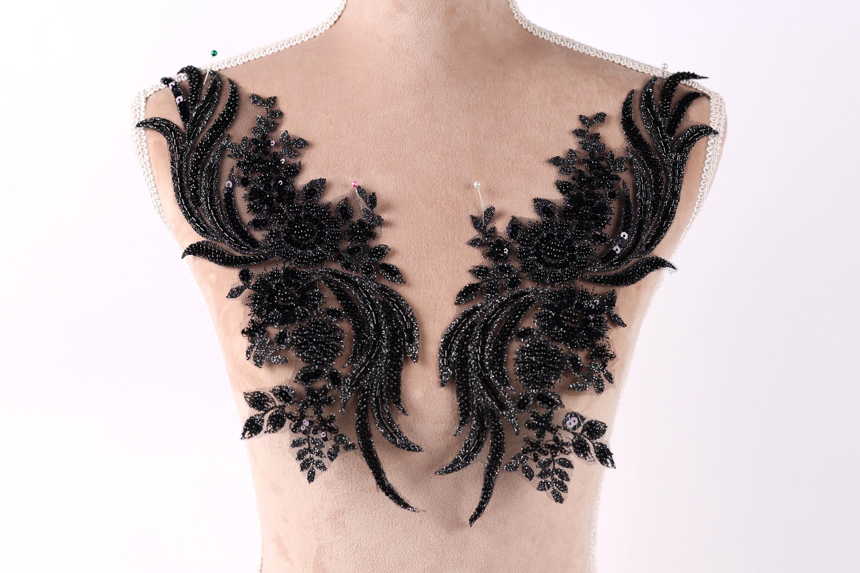 a mannequin torso with black, intricate, and ornate black lace or sequin pieces attached to it, creating a striking and elegant appearance.