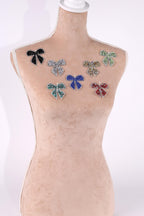 A mannequin is wearing a beige dress with various colorful bow-shaped embellishments on its chest area.