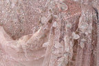 The image is a close-up of a delicate, intricately designed fabric with a pink and white color scheme. The fabric features a floral pattern and is adorned with sequins, giving it a sparkling and elegant appearance.