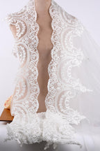 A close-up view of a delicate, white lace veil with intricate floral patterns.