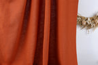 a close-up view of a red fabric, possibly a curtain or a piece of clothing, with a wreath of dried flowers visible in the background.