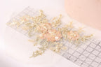 a close-up view of a delicate floral embroidery with gold and white flowers, placed on a transparent surface.