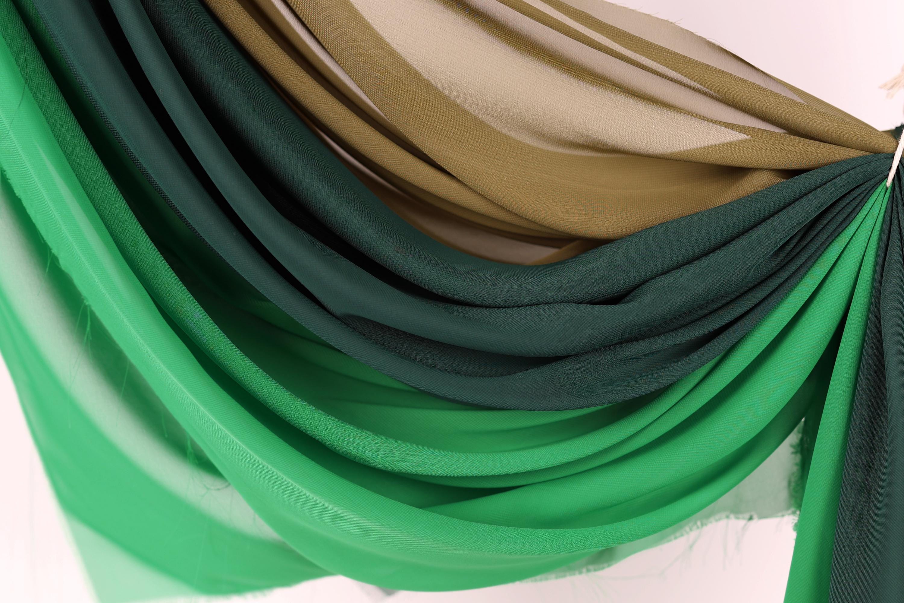 a close-up view of a fabric with a gradient of green and brown colors, creating a visually appealing and textured appearance.