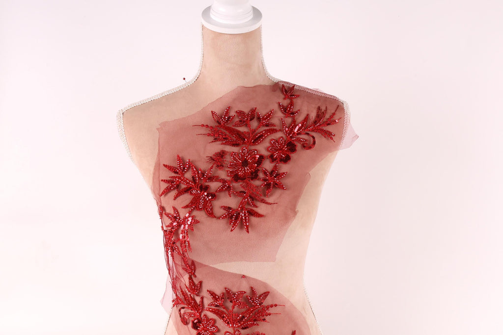 A mannequin with a red floral embroidered on its body, set against a plain white background.