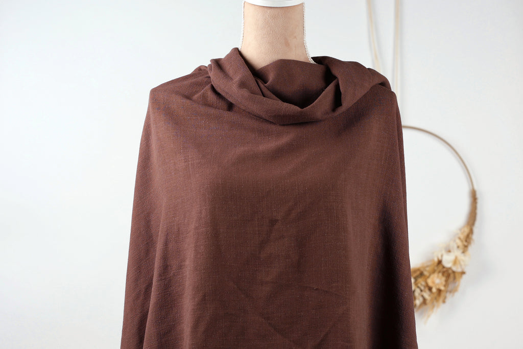 A mannequin wearing a brown, knitted garment with a scarf draped over it, displayed against a white background.