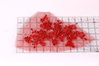 a piece of red fabric with intricate red floral designs, laid out on a transparent ruler for scale.