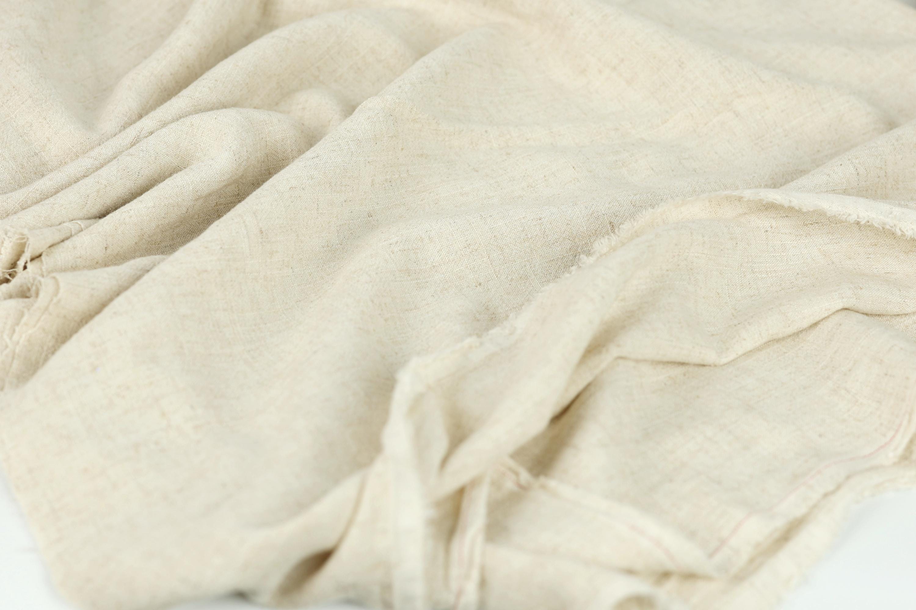 A close-up view of a crumpled, light-colored fabric, possibly a piece of linen or a similar material.