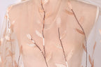 A mannequin wearing a sheer, peach-colored dress with delicate leaf-like embroidered patterns.