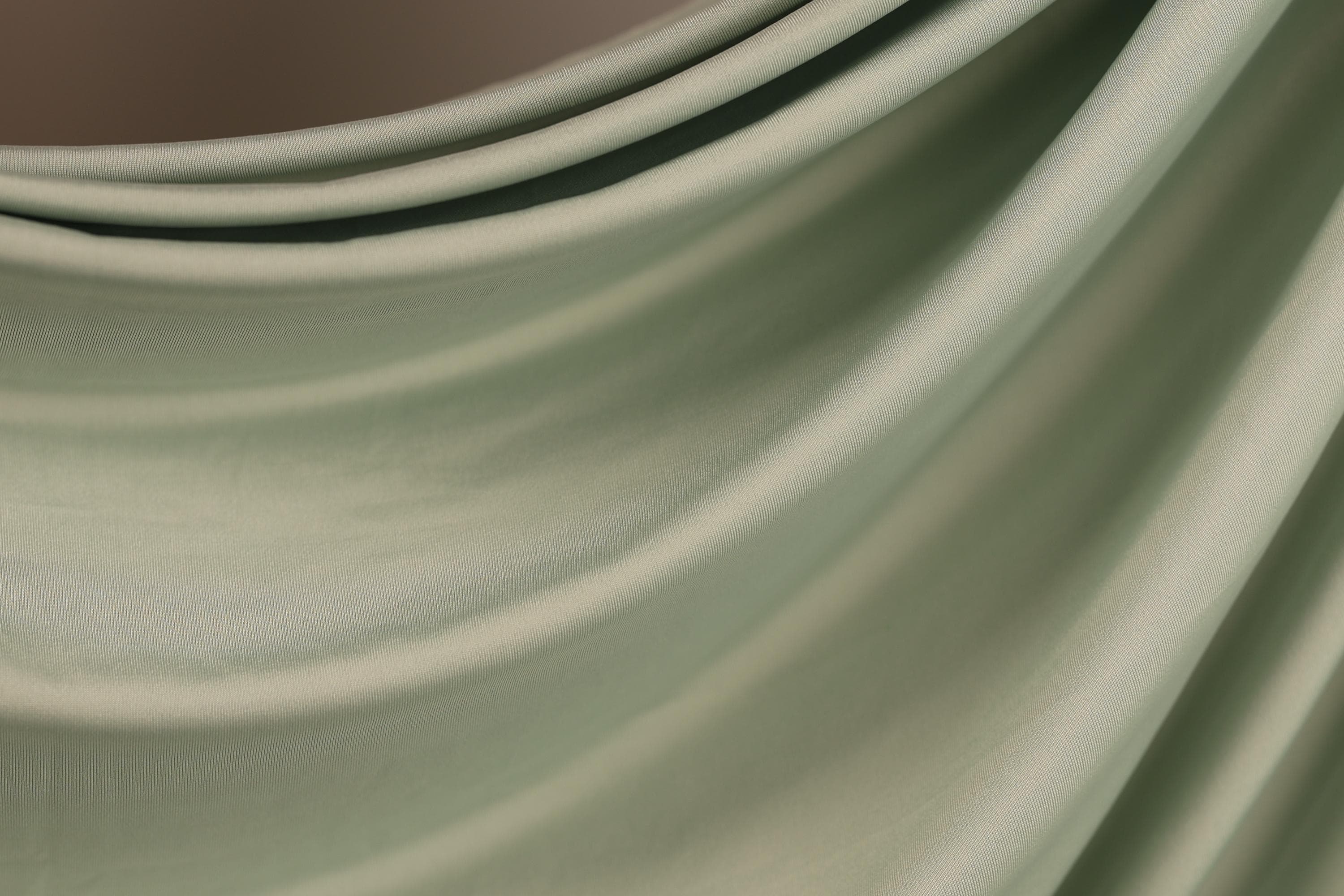 a close-up view of a fabric with a smooth, flowing texture in a light green color.