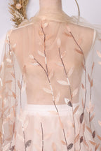 a mannequin wearing a white dress with a sheer, floral-patterned fabric draped over it. The dress has a delicate, lace-like design with a floral motif.