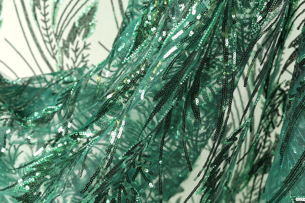 The image is a close-up view of a fabric with a green and black sequined pattern, featuring a lot of small sequins and beads that create a textured and intricate appearance.