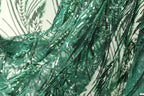 The image is a close-up view of a fabric with a green and black sequined pattern, featuring a lot of small sequins and beads that create a textured and intricate appearance.