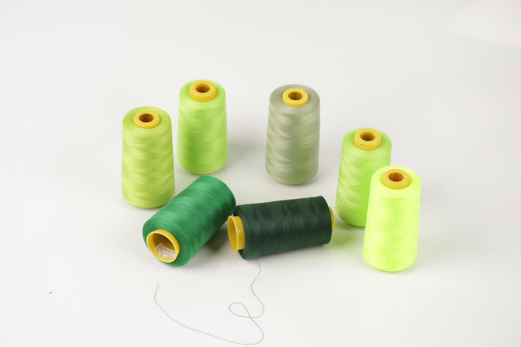 a collection of green and yellow thread spools arranged on a white background.