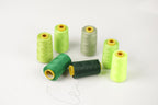 a collection of green and yellow thread spools arranged on a white background.