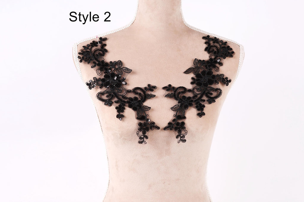 A mannequin wearing a black lace dress with intricate floral patterns.