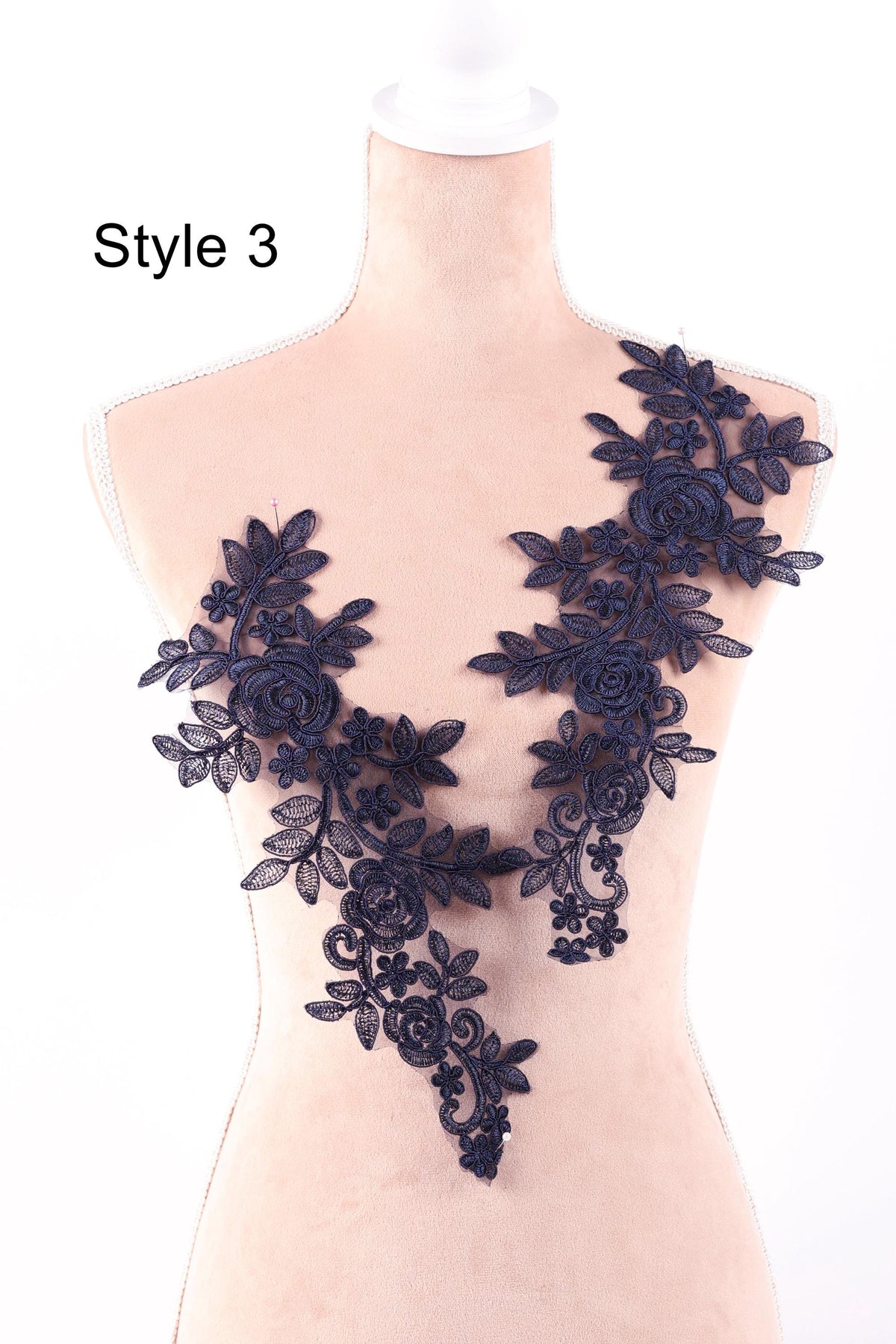 A mannequin wearing a dress with a floral lace design on the shoulder.