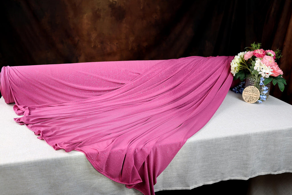 a pink blanket on a white table with a vase of flowers