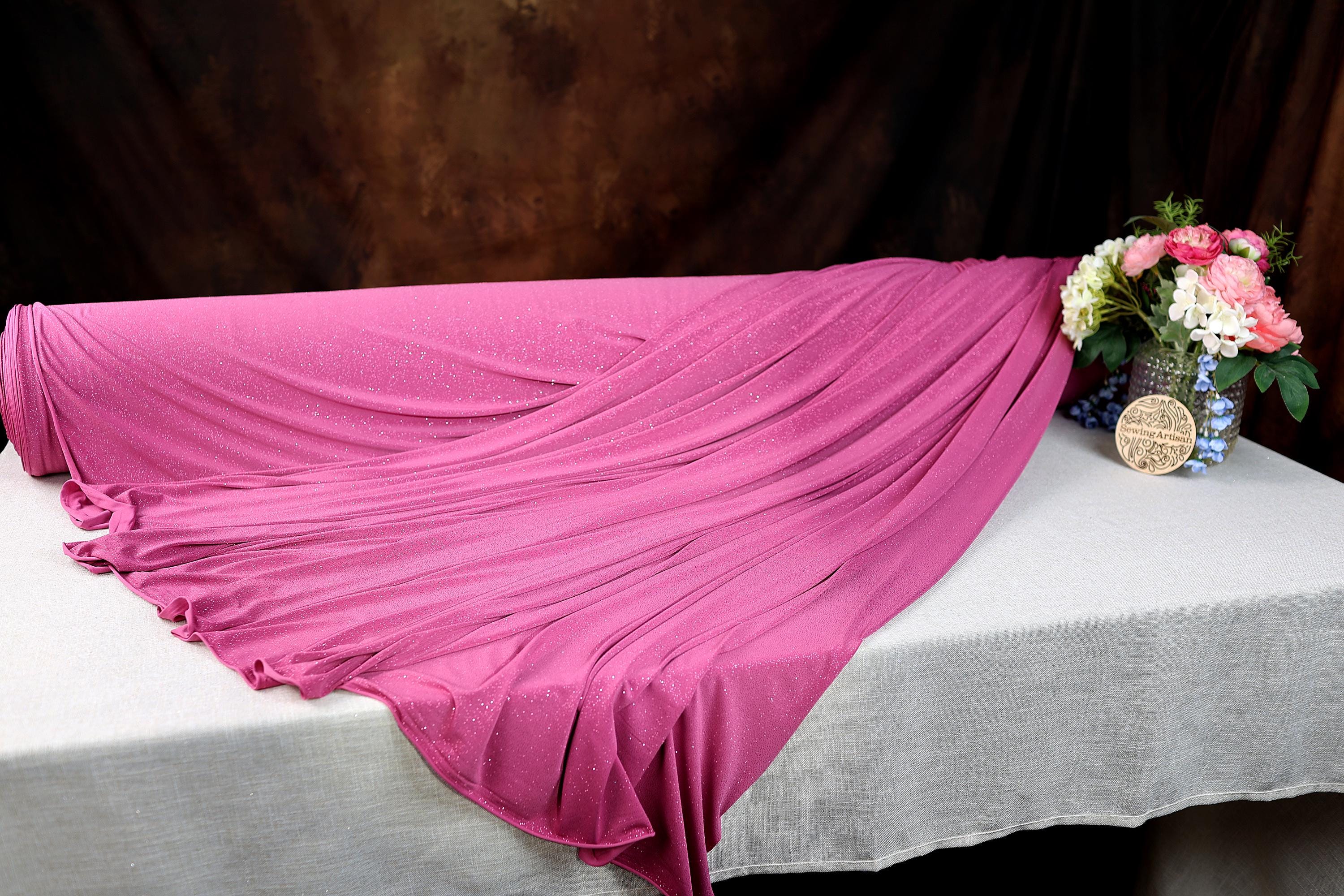 a pink blanket on a white table with a vase of flowers