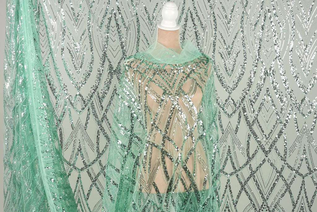 a mannequin wearing a sequin dress with a mint green color. The dress has a shimmering, sequined pattern that creates a visually striking appearance.
