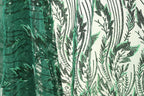 a close-up view of a fabric with a green and black leaf pattern. The fabric appears to be made of a sheer material, with a repeating pattern of green leaves and black lines. The leaves are arranged in a vertical orientation, creating a sense of depth and texture in the image.