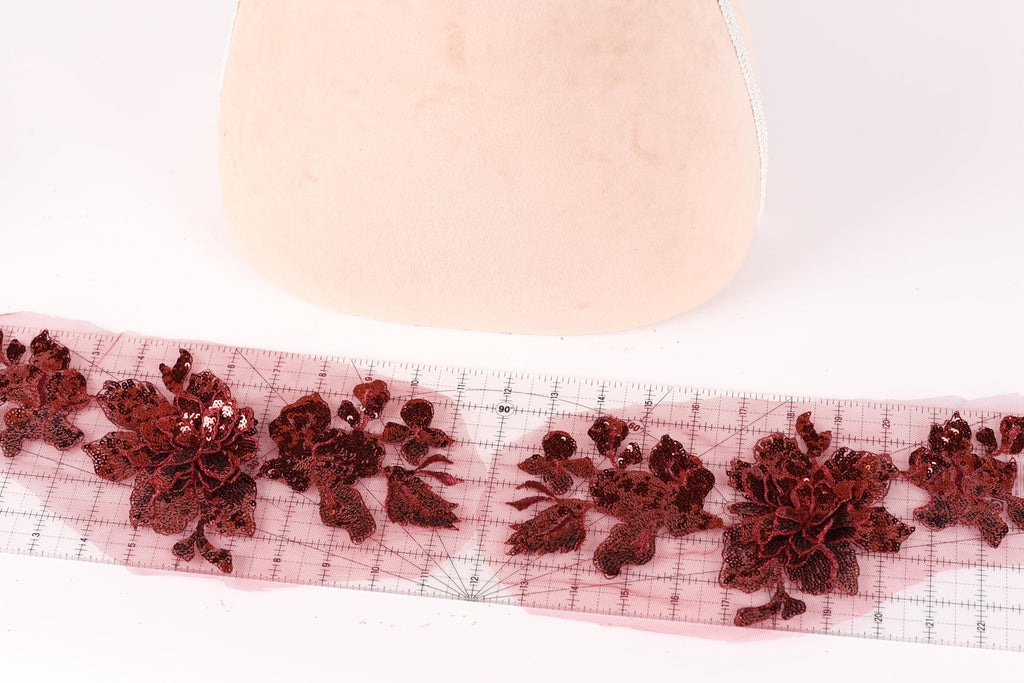 a pink object with red floral designs on it, placed on a pink surface. There is a ruler visible in the image, which is likely used for measuring or marking purposes.
